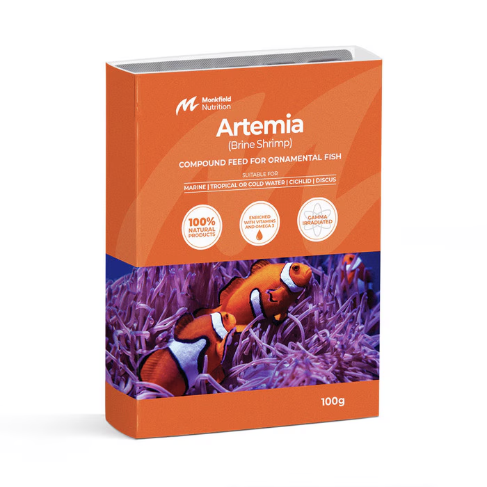 Packaging of Monkfield Nutrition Artemia (Brine Shrimp) compound feed for ornamental fish, featuring an orange box with clownfish swimming among purple coral, suitable for marine, tropical, cold water, cichlid, and discus fish, enriched with vitamins and omega-3, and gamma irradiated for safety