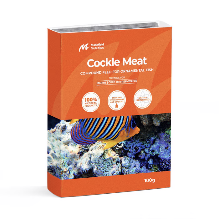 Packaging of Monkfield Nutrition Cockle Meat compound feed for ornamental fish, featuring an orange box with an image of a striped marine fish swimming near coral, suitable for marine, cold, or freshwater fish, enriched with vitamins and omega-3, and gamma irradiated for safety.