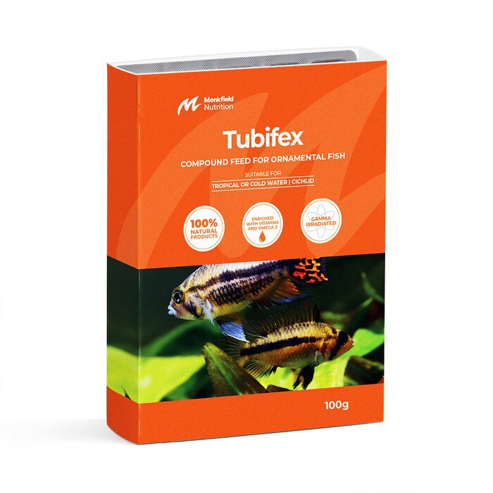 Packaging of Monkfield Nutrition Tubifex compound feed for ornamental fish, featuring an orange box with an image of tropical fish swimming near aquatic plants, suitable for tropical or cold water and cichlid fish, enriched with vitamins and omega-3, and gamma irradiated for safety.